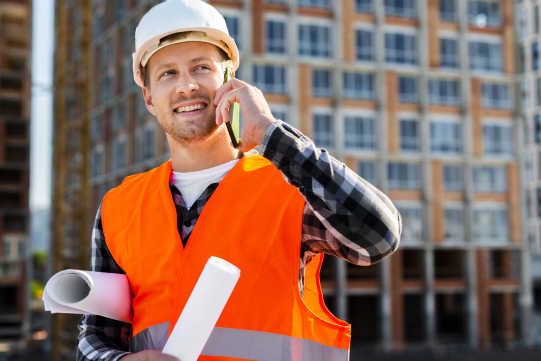 Мужчина бригадир улыбается и говорит по телефону