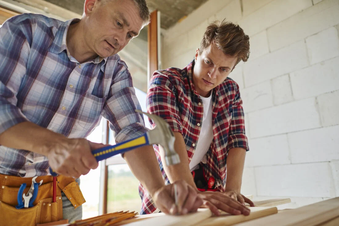 Мужчины плотники забивают гвоздь молотком Нидерланды