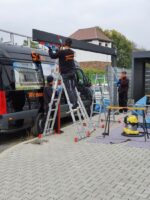 Монтажник алюминиевого навеса напротив черного автомобиля