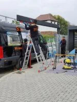 Монтажник алюминиевого навеса напротив черного автомобиля