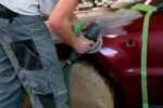 Мужчина шлифует боковую сторону автомобиля