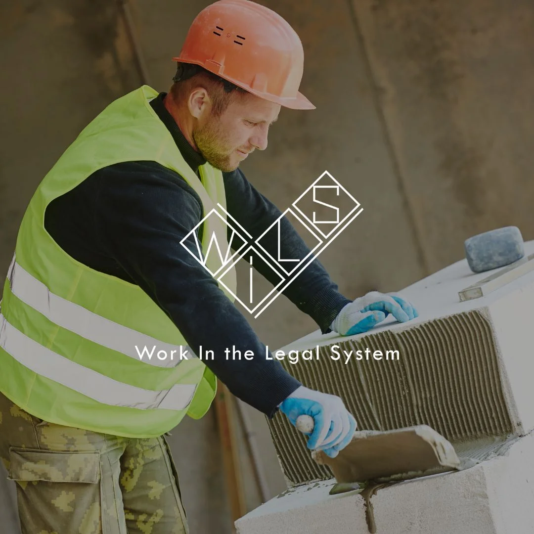 Молодой мужчина в желтой строительной жилетке и оранжевой каске на стройке наносит бетонную смесь