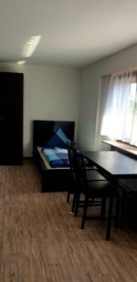 Фото комнаты хостела с кроватью, столом, стулом и окном