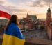 Девушка с украинским флагом на фоне Старого города Варшавы и польского флага